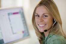 Smiling woman with headset and computer monitor